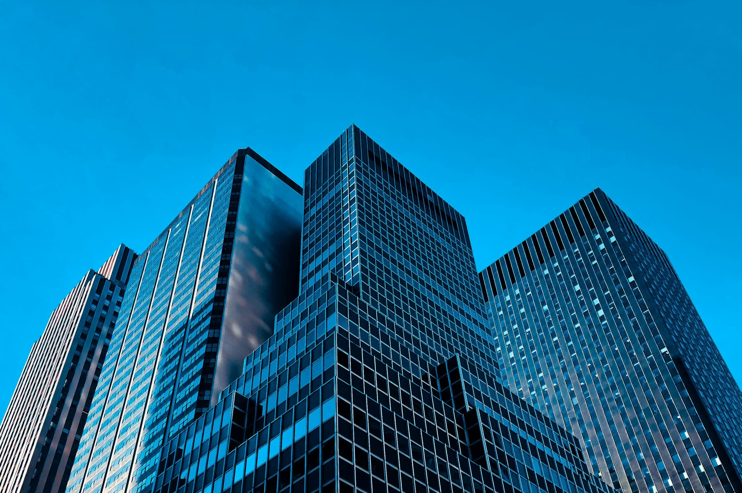 Glass office towers seen from street level against a clear blue sky